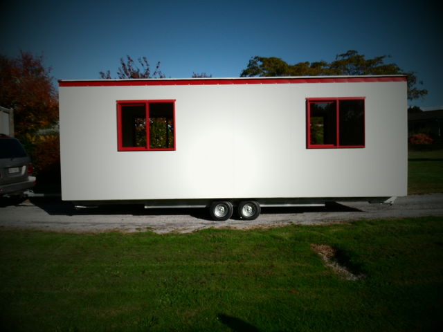 white cabin with red trim sitting on trailer